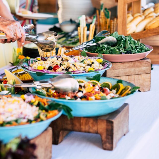 close up of view of table full of food with someone taking pasta of the table to celebrate - caucasian woman
