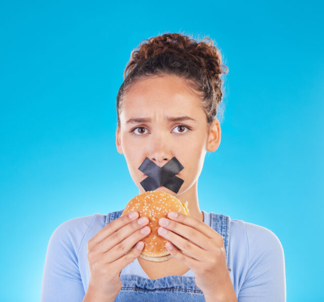 Burger, diet and woman reject fast food choice and unhappy gives bad, disgust and frustrated review for protection. Disaster, mistake and person disappointed isolated in a studio blue background